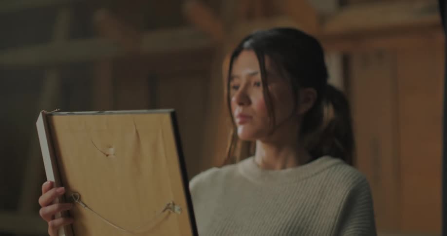 A woman is putting frames on pictures