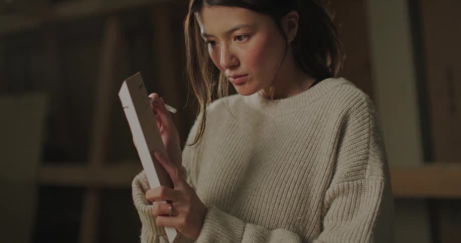 Young woman marks timber with pencil