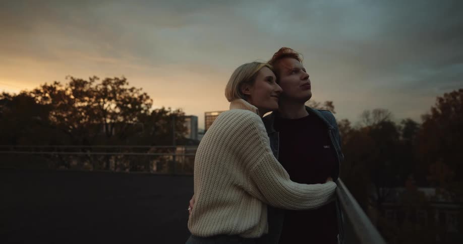 Happy couple hugging on the roof of a building at evening