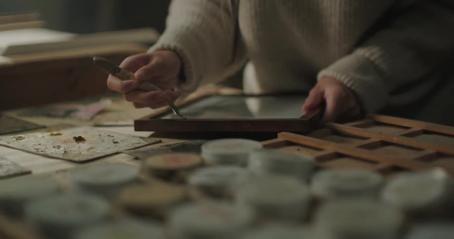 Close up of an artist working on a frame with a tool inside her workshop
