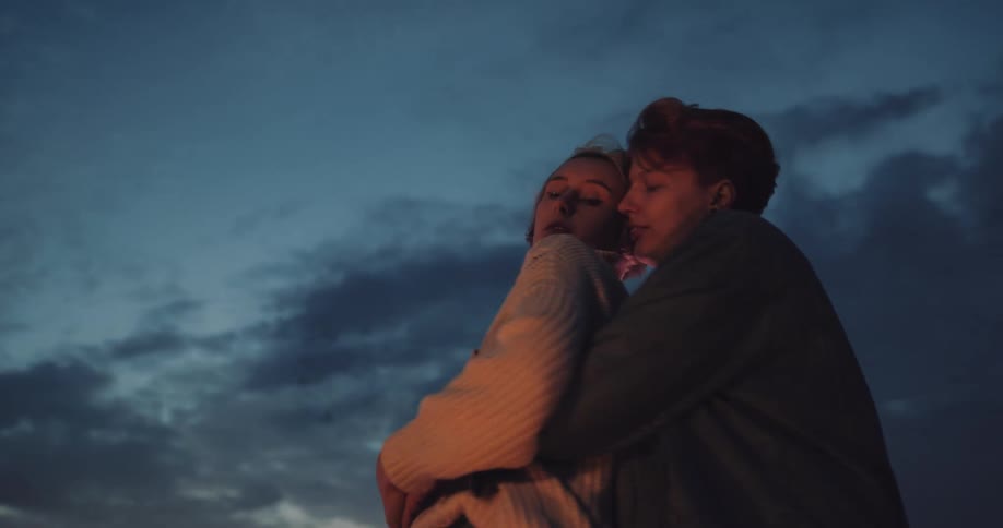 Two women hold one another and dance on a rooftop