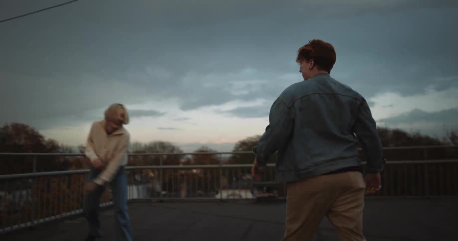 Young happy couple playfully dancing on the roof of a building at evening