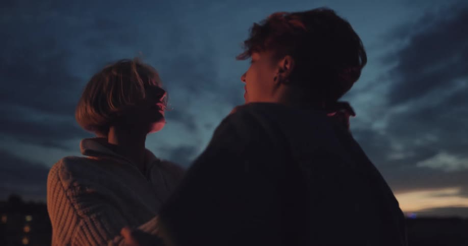 Young couple romantically dancing on the rooftop of a building at evening