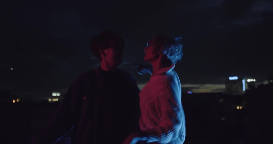 Two women dancing on the rooftop at night in the city