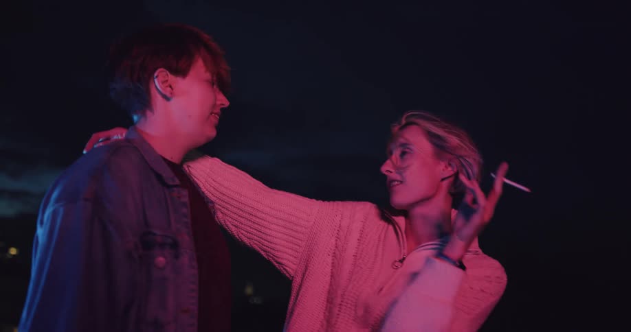 Two women dance on a rooftop at night