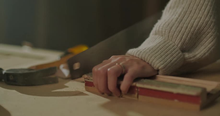 Woman sawing wood in woodworking workshop