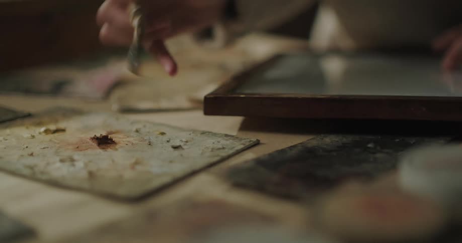 Young woman putting varnish on a wooden frame