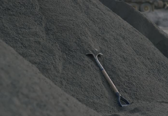 Ground gravel rolls down over a shovel on a mound