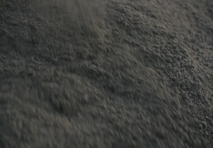 Grey sand slides from top left to bottom right with a poof of dust