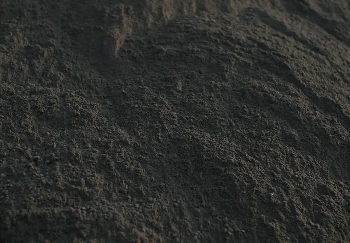 Soil rolls down a large hill of dirt