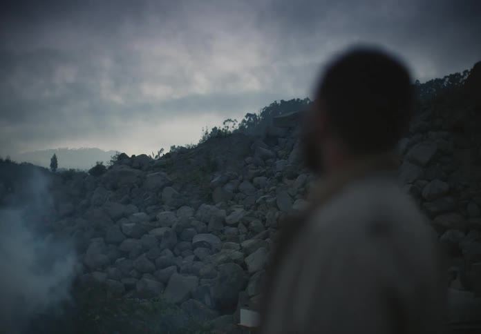 A man stands by a hill of stones