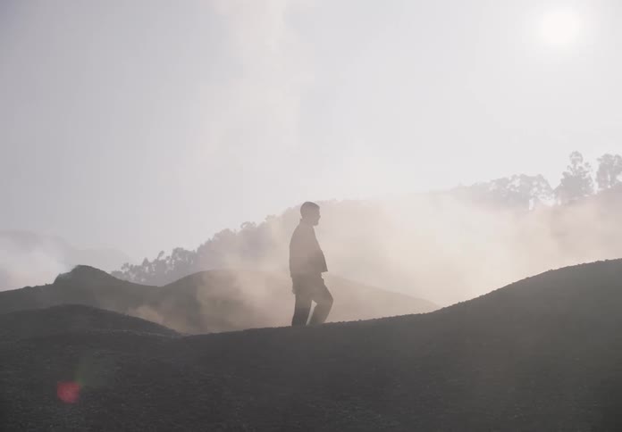 A man walks over mounds of gravel at a gravel pit