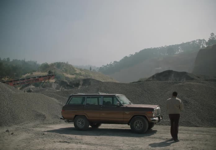 A man at a gravel pit looks around and then runs to his car and drives away