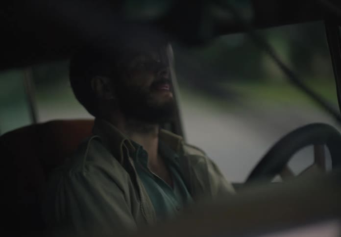 A man is driving an automobile and turning the steering wheel and he stops with a sigh of relief and gets out of the vehicle leaving the door open as he walks away