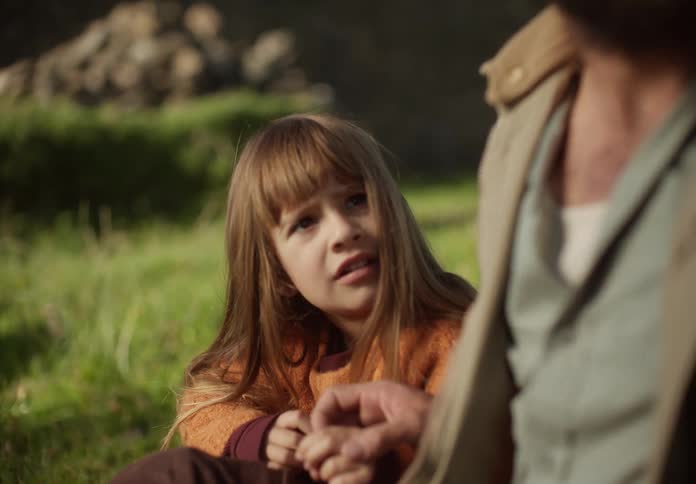 Father and daughter sitting on the grass in the backyard looking at flowers