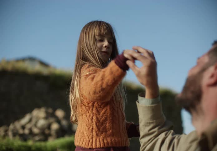 A little girl hits her dads hand and then they wiggle their fingers together and laugh