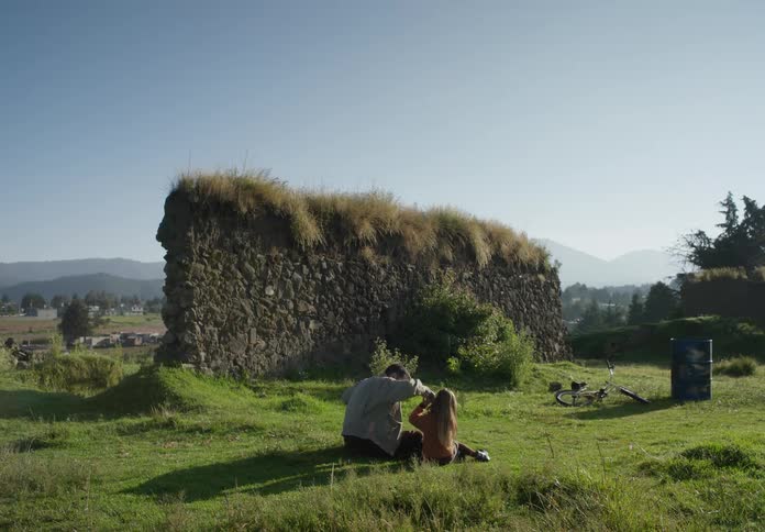 A man sits with young girl on the grass as they interact playfully