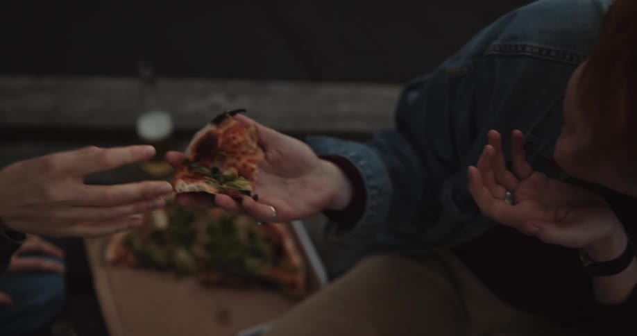 Two women feed pizza to each other