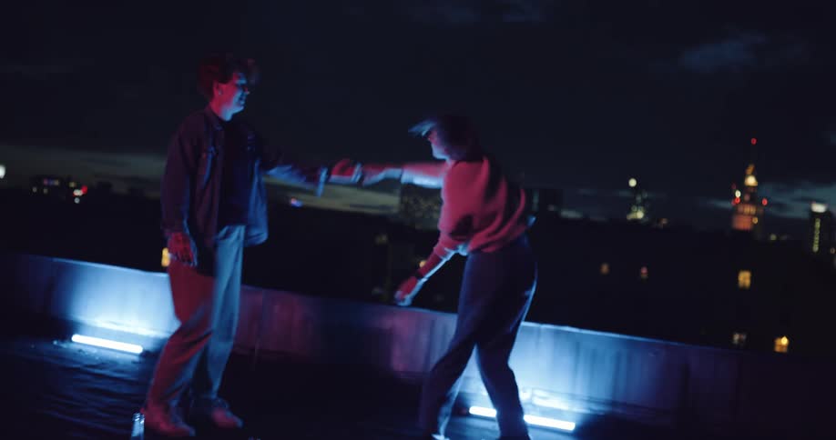 Two women dancing in front of flashing lights on their rooftop