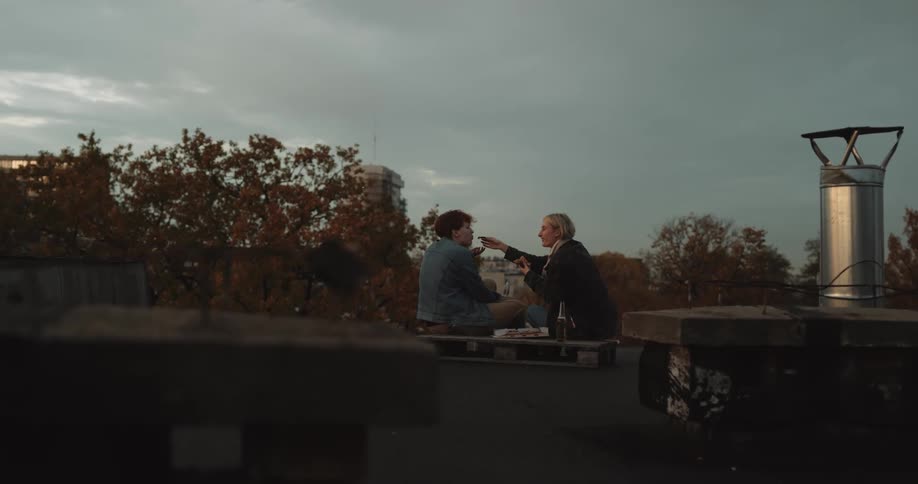 A woman feeds food to her partner while they picnic in a park