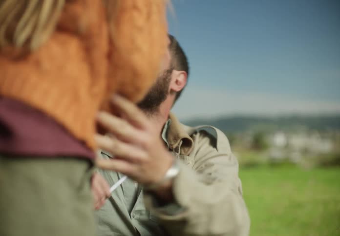 A girl trying to take a cigarette away from a man while he smiles and lights it