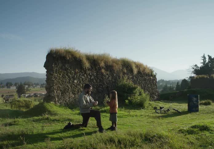 Father and daughter play with firecracker near stonewall on hill overlooking valley town