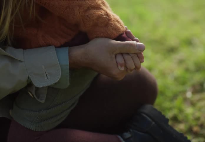 A man pulls his daughter in to sit on his lap on their lawn