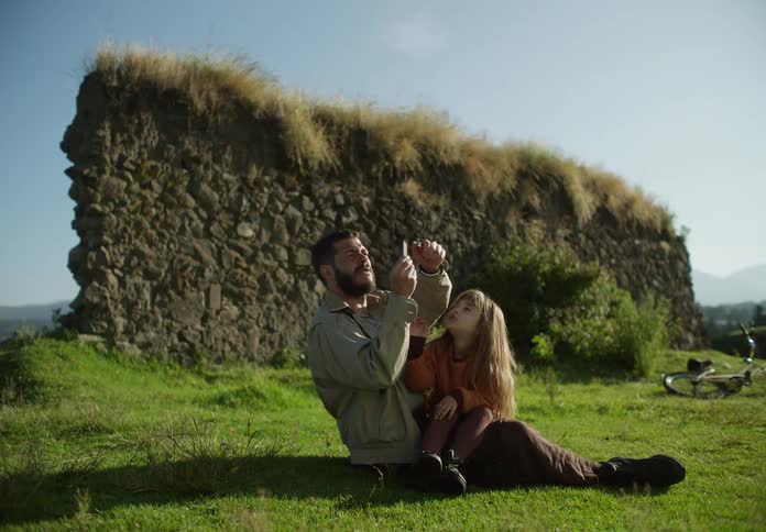 A man holds a girl in his lap and lights off a firecracker