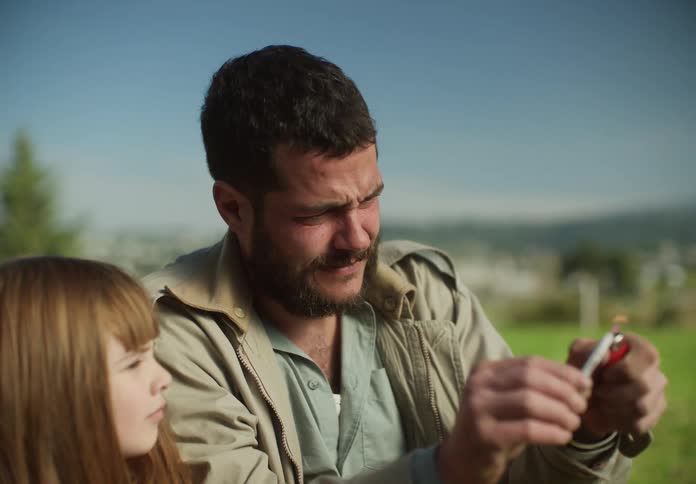 Father sitting with his daughter on the lawn in the countryside throwing firecrackers