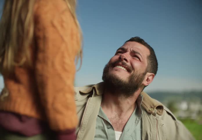 Father and daughter look at each other smiling and laughing while sitting outside