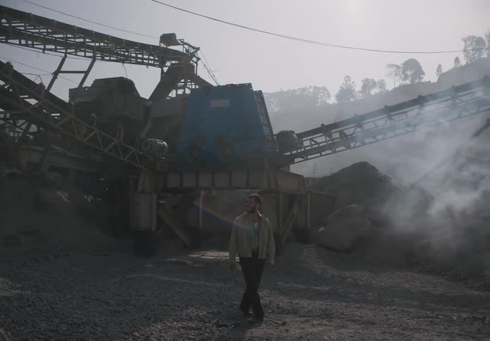 A man walks through a construction site as dust blows around him