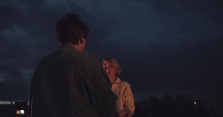 A couple dance outside their city at night