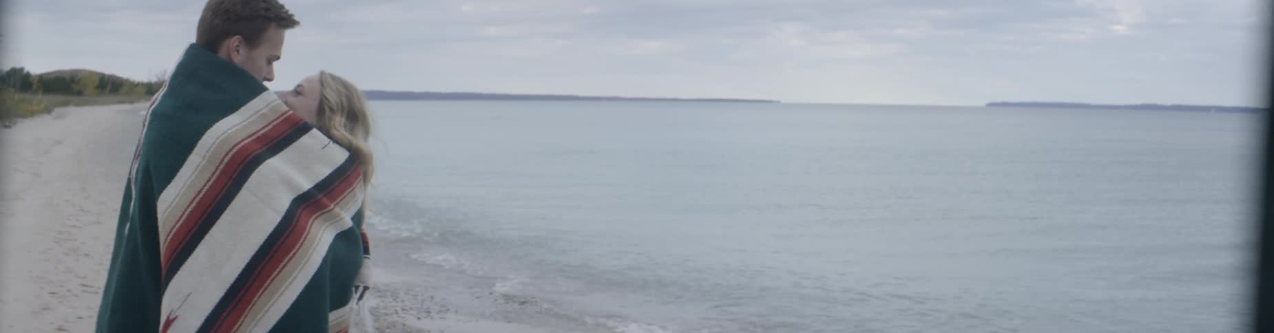 A man and woman are hugging on the beach