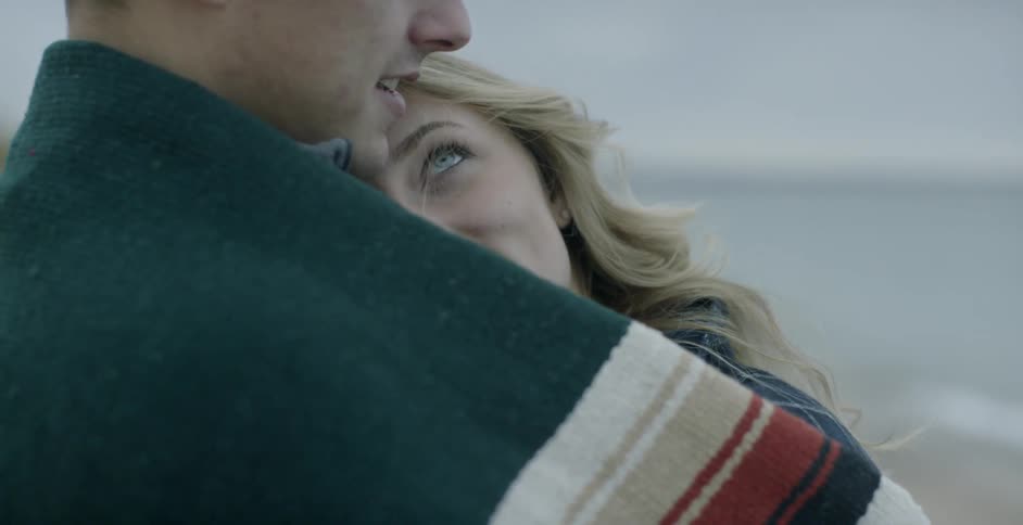 A man and woman hug and talk on a beach