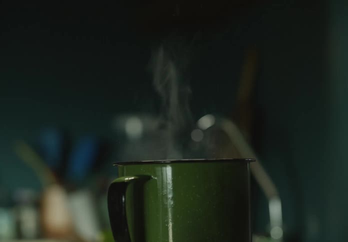 Steam rises from the rim of a metal coffee mug