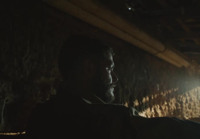 A young white man is inside of his home just hanging out