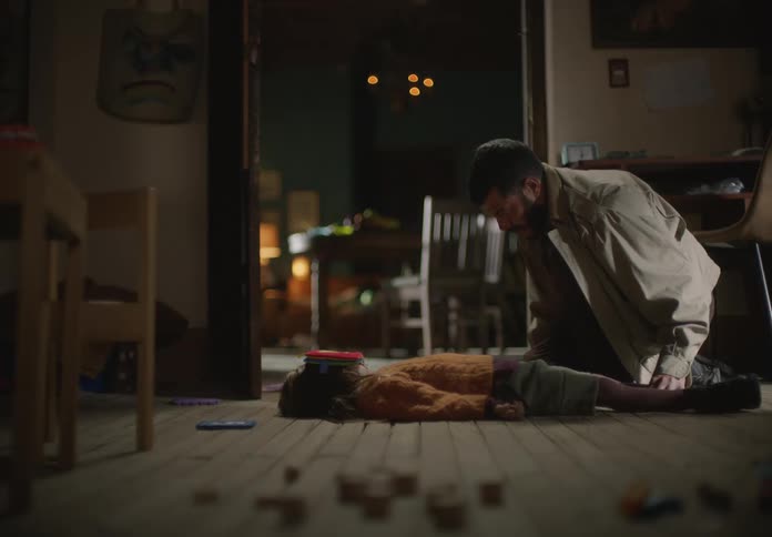 Father kneeling besides her daughter laying on the floor waiting for her to move