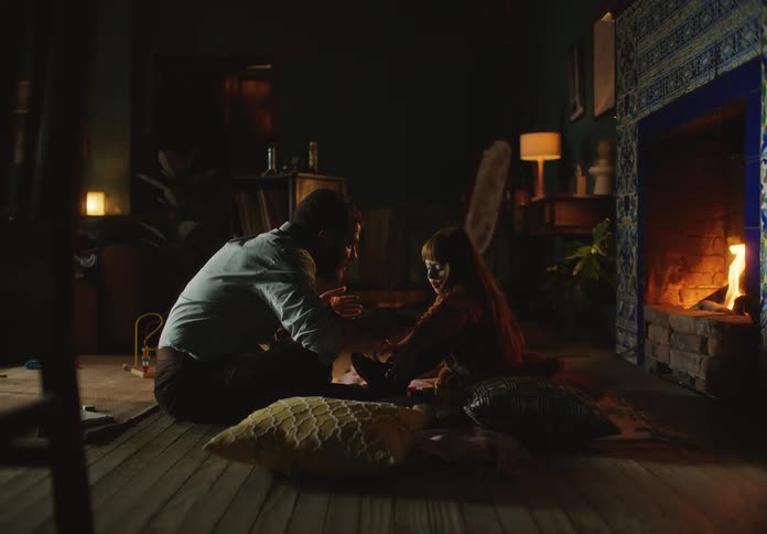 Father and daughter sitting in front of a fireplace at home
