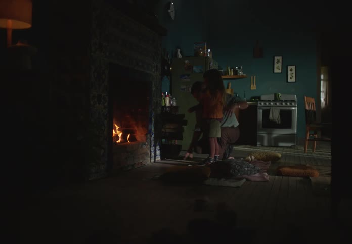 Father stirs fireplace hugging daughter before he burns himself picking pot off nearby stove