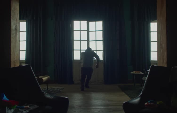 A young white man is inside of his room in the middle of the day