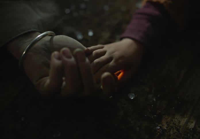 A man holds his daughters hand while they lie on the ground outside
