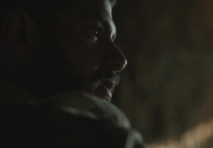 A man gazes out from the darkness towards the sunlight shining into the tunnel he is in