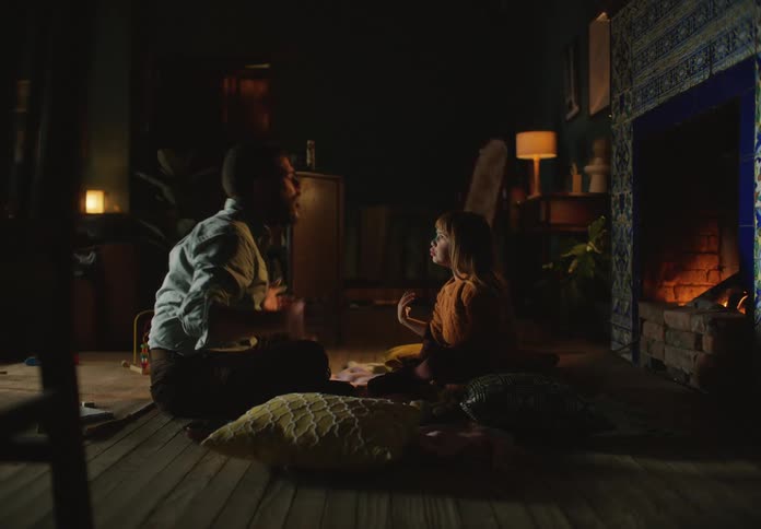 Father and daughter howl while playing together near lit fireplace
