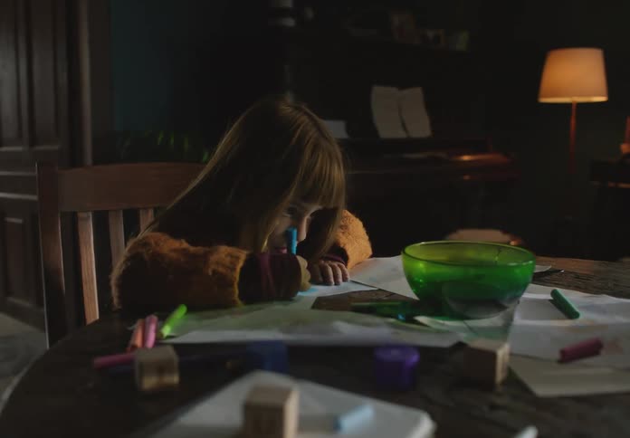 A young kid is sitting down in a chair and coloring a picture