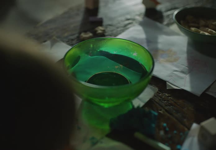 A kid is coloring a picture at the table in the middle of the day
