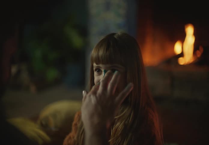 Father paints the face of his happy daughter in front of the fireplace