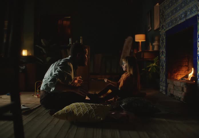 Father and daughter sitting in front of the fireplace playfully howling to each other
