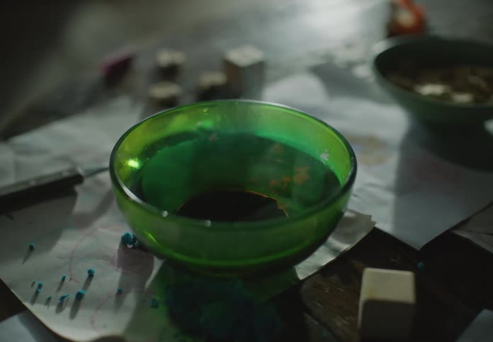 Two bowls sitting on table with pigmentspread on papers tremble as surface vibrates