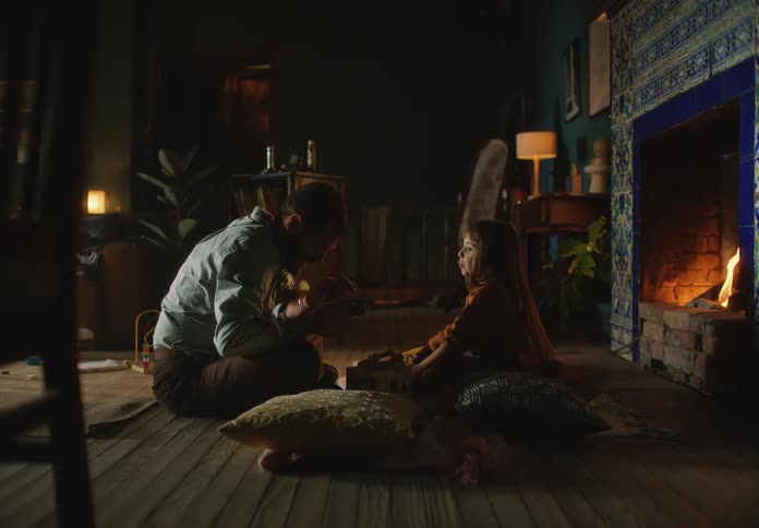 Father and daughter sitting in front of the fireplace telling stories to each other