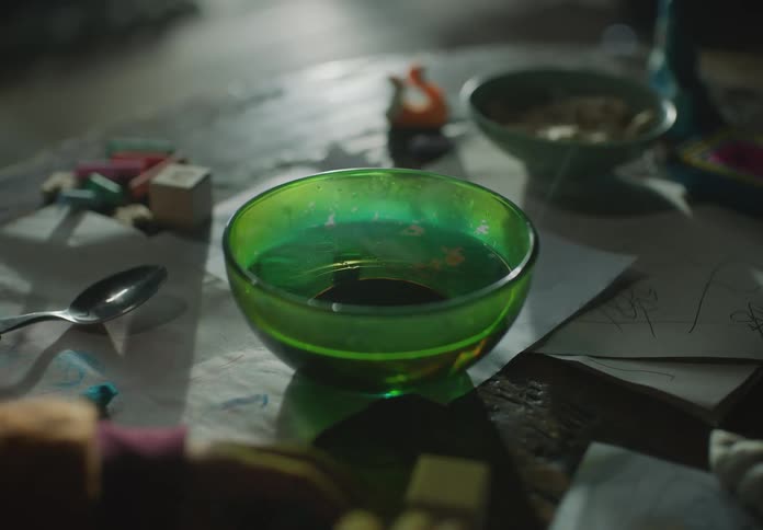 Child sits at table near bowl of warm liquid playing